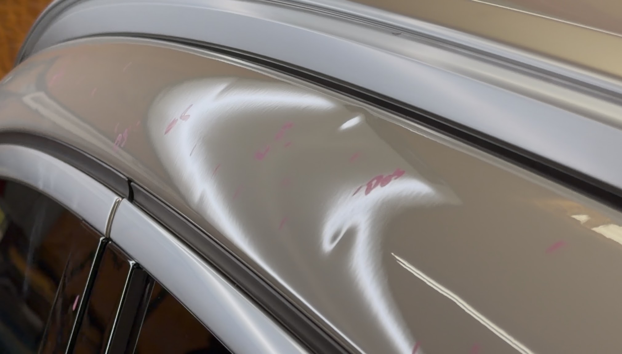 Hail dent on a panel with each low spot marked before paintless dent repair