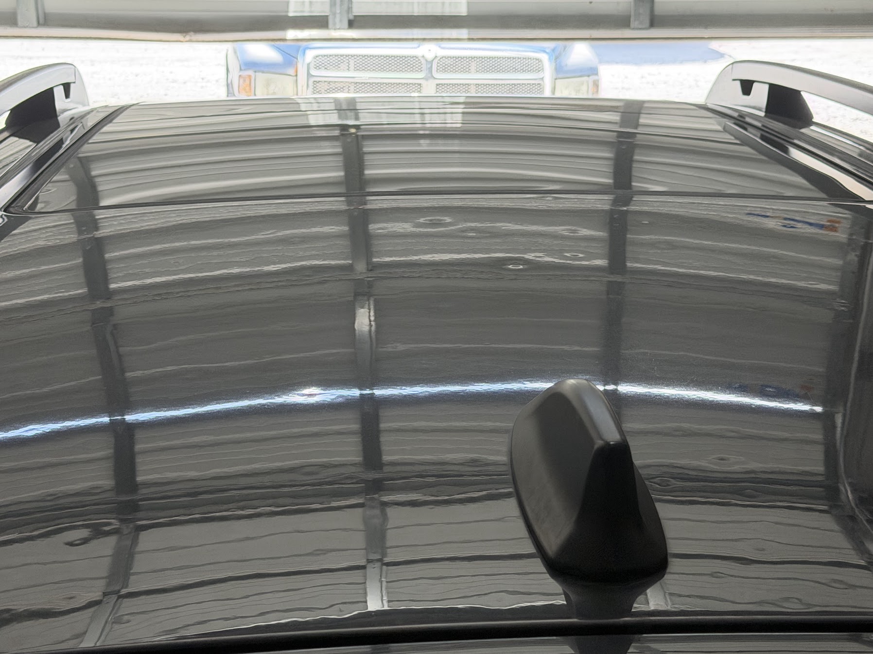 Hail dimples visible in the natural reflection on a car roof
